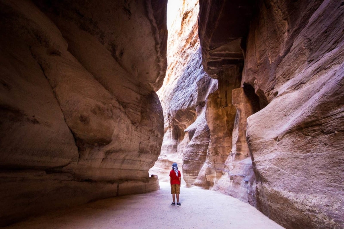 A small boy is enveloped by the walls of the Siq at Petra
