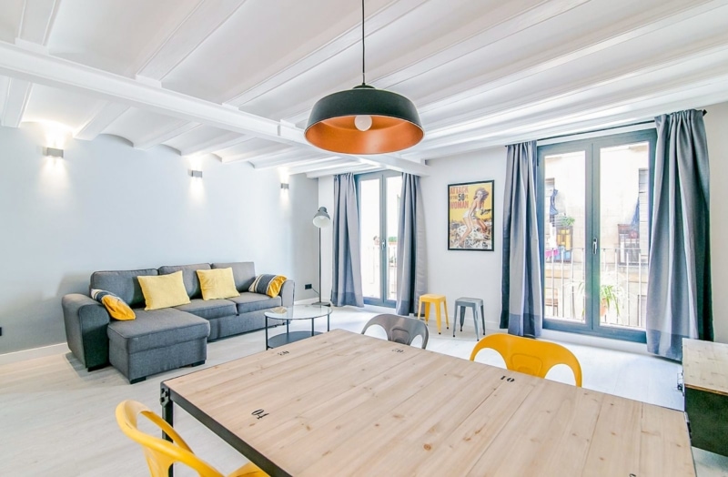 a modern apartment with grey couches and yellow chairs