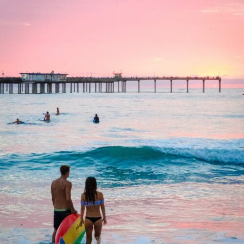 Surfers watch the sunset on Ocean Beach in San Diego along the Pacific Coast Highway