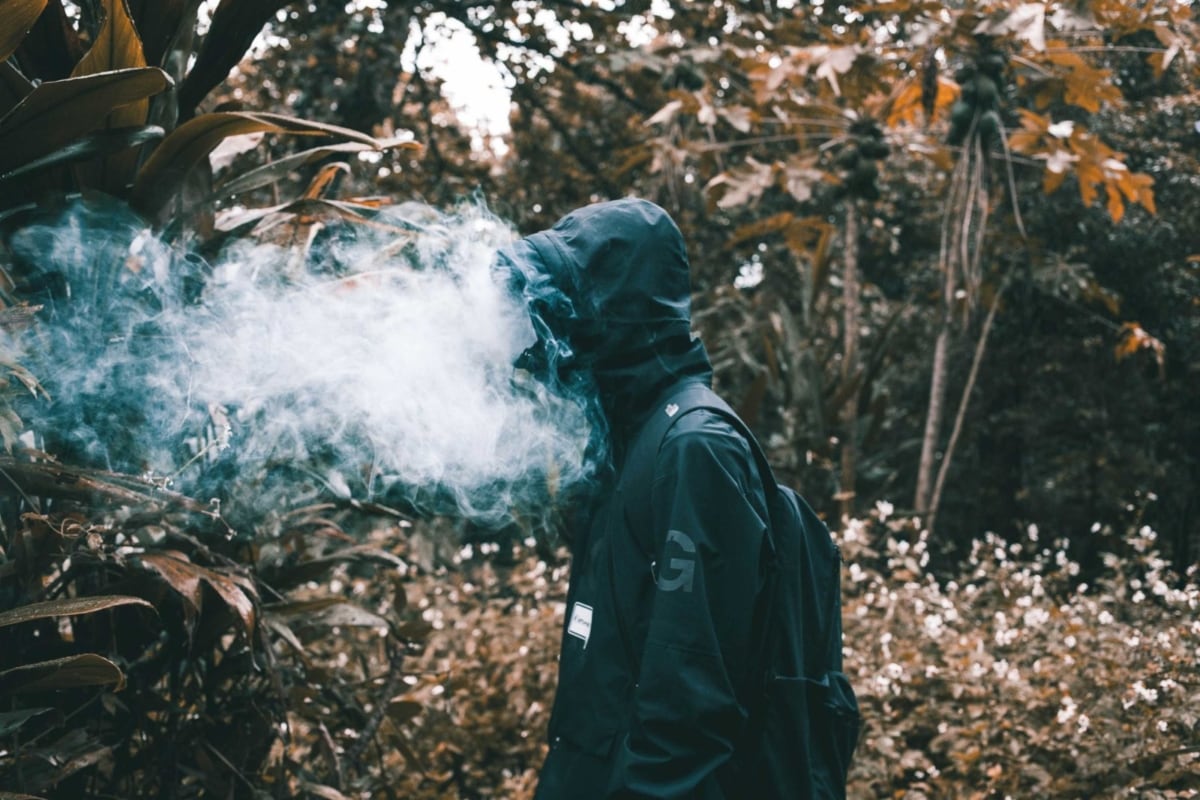 Person with hoodie and smoke near his face