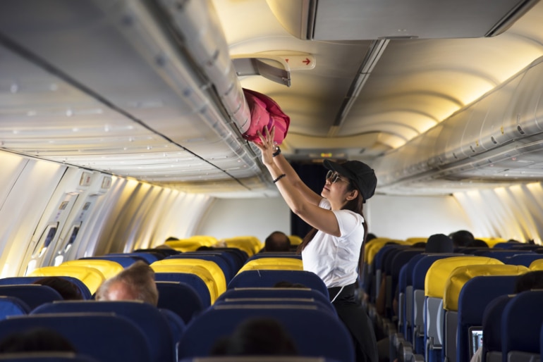 Air Hostess open overhead locker on airplane