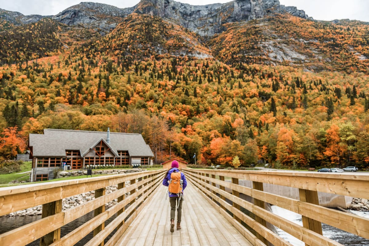 A woman walking in Quebec surrounded by fall colors in nature.