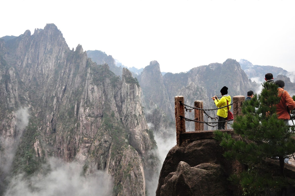 a woman stands at a lookout taking photos of a gorge in China