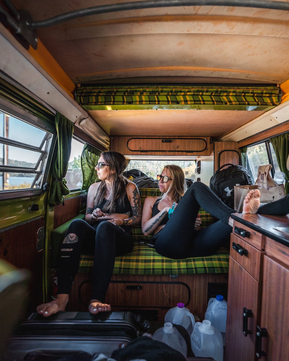 Two girls lounging in the back of a campervan