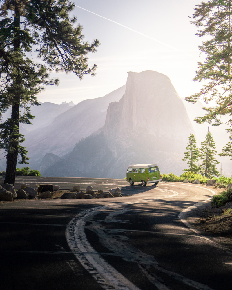 A green campervan winding through the mountains