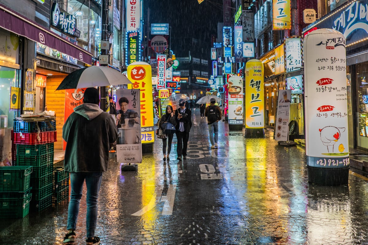 People walking through a rainy city streetscape in Asia
