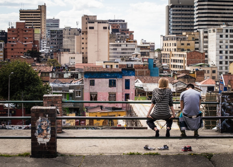 a couple sit on a bench overlooking the city of Bogota