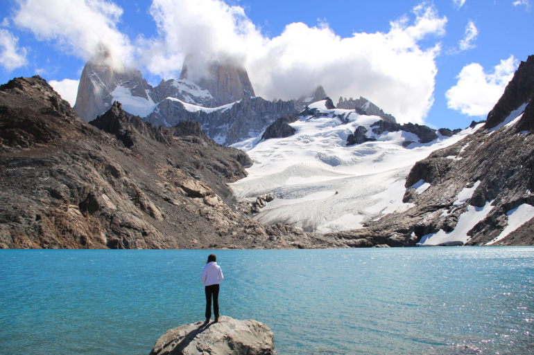 a person dressed in white looking at the glacier and lake of El Chalten, Argentina