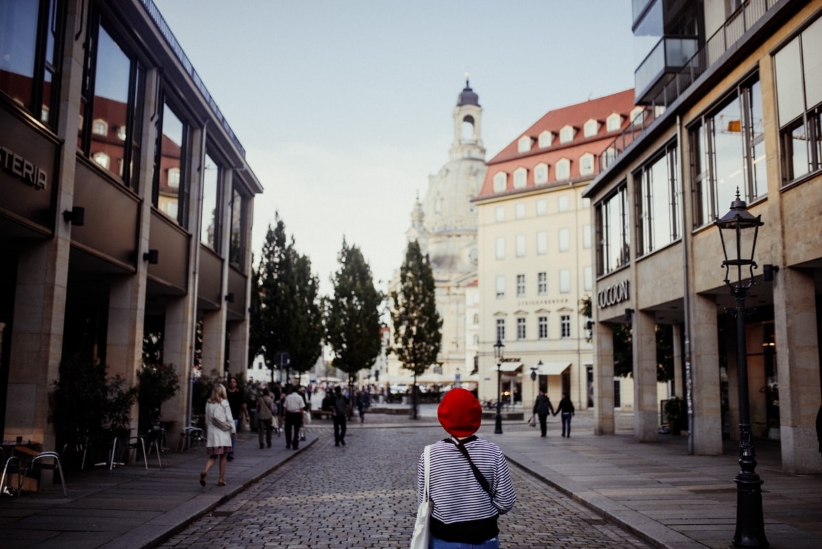 a woman wearing a red hat walking down the street in Dresden, Germany