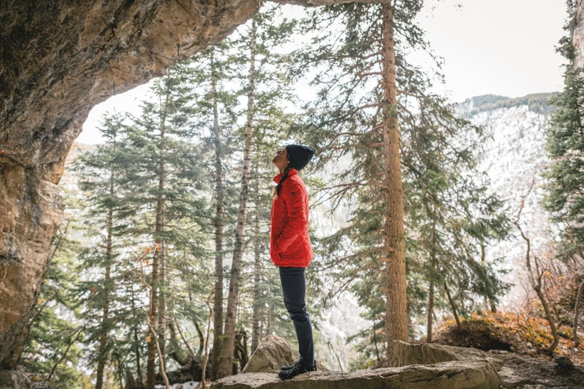 woman wearing a red Columbia jacket looking up into the trees