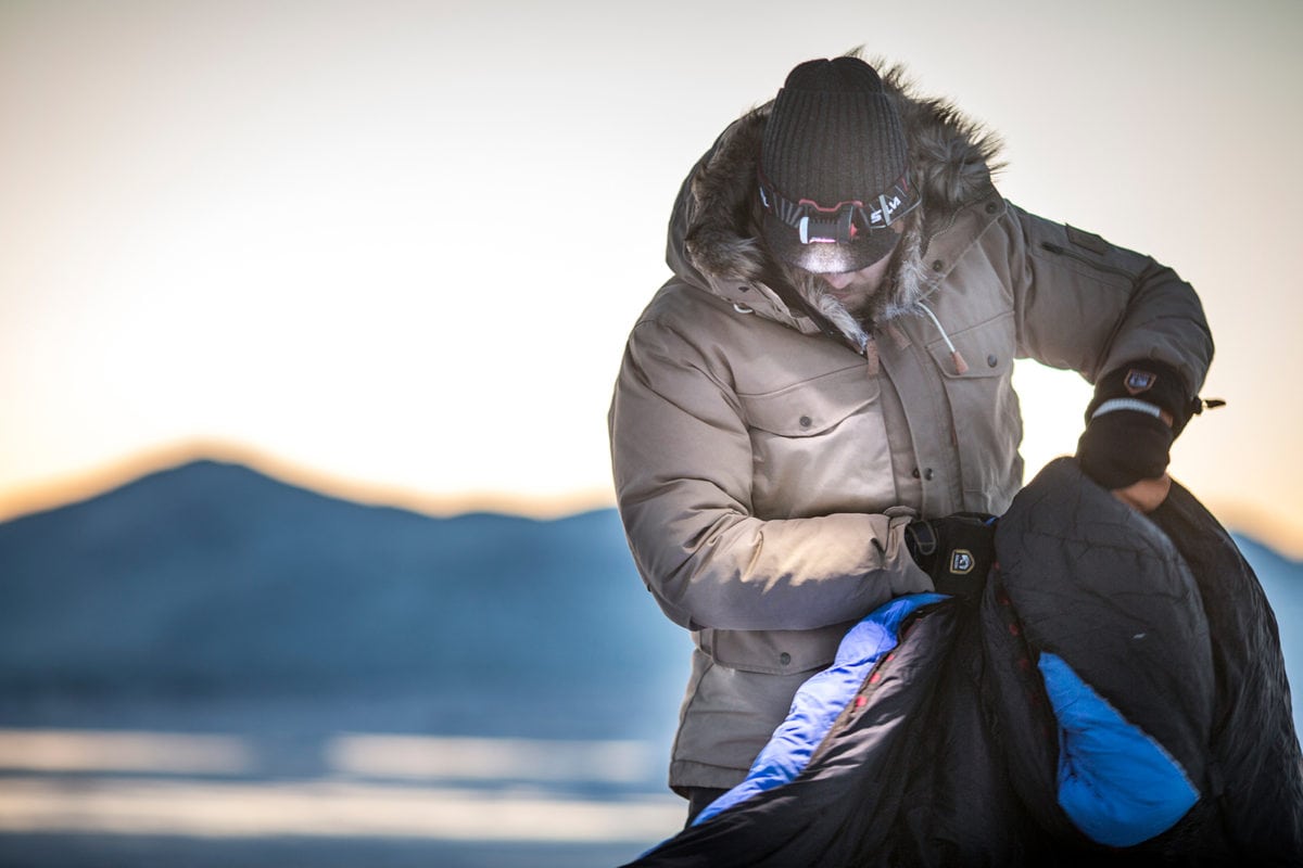 a man setting up a tent while wearing a Fjällräven winter jacket